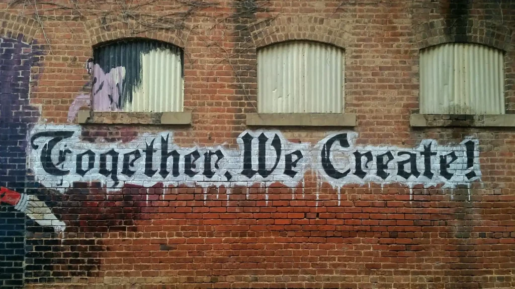 Abstrakte Kunst an einer Hausmauer mit der Aufschrift "Together we create!"