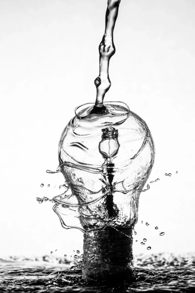 Symbolisches Bild einer Glühbirne über die Wasser geschüttet wird